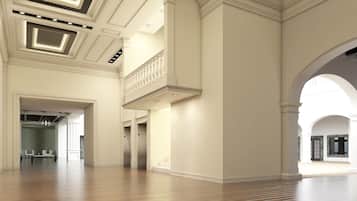 Un interior espacioso con techos altos, piso de madera y una imponente escalera.