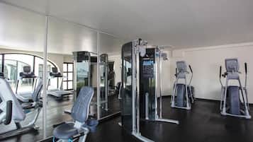 Un gimnasio con diversos equipos de ejercicio, incluyendo cintas de correr, elípticas y máquinas de pesas.