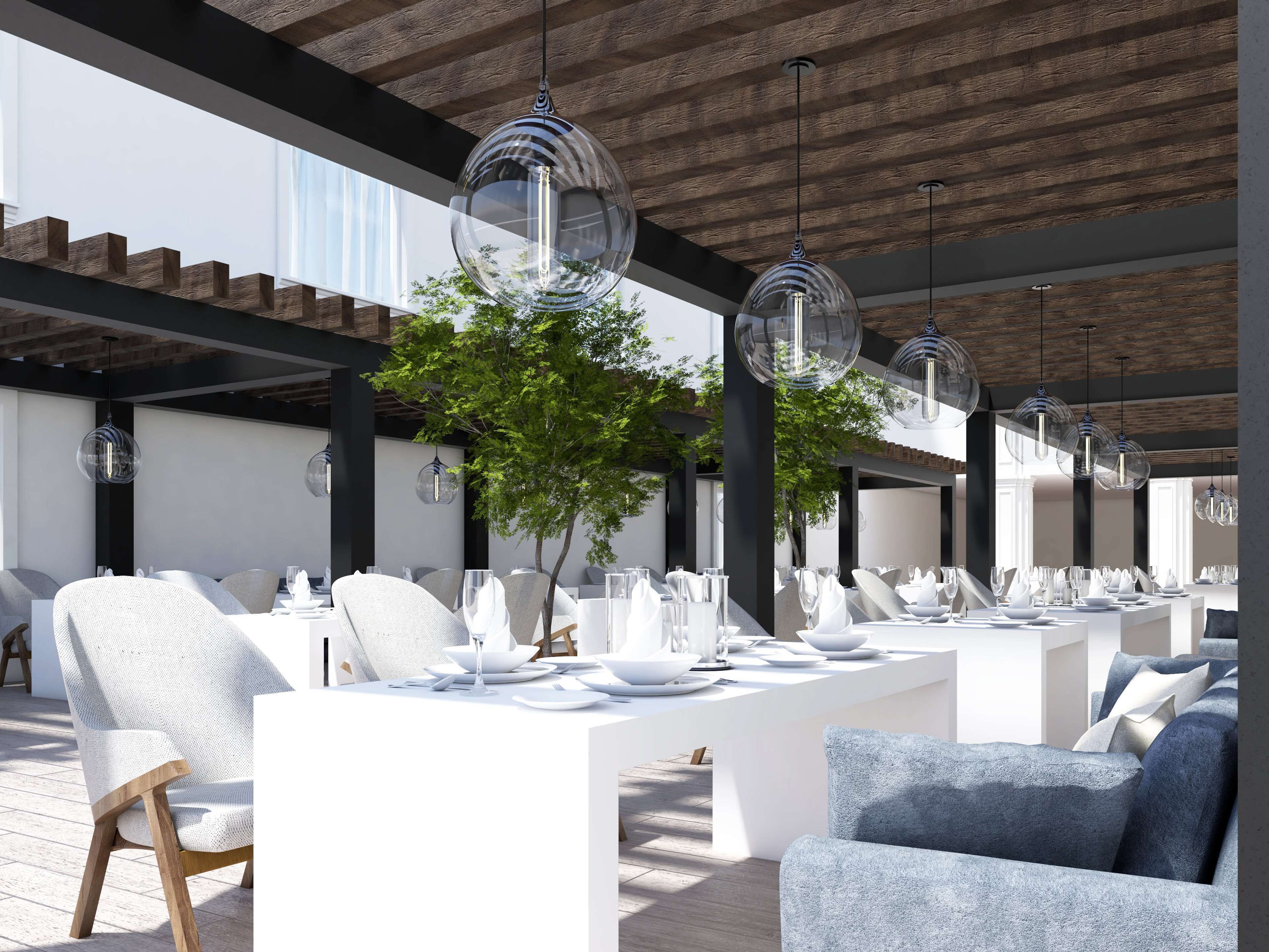 An outdoor dining area with white tables and chairs, clear glass pendant lights, and a wooden ceiling.