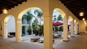 Une cour intérieure dotée d’arcades, d’espaces aménagés pour s’asseoir et de plantes en pot.