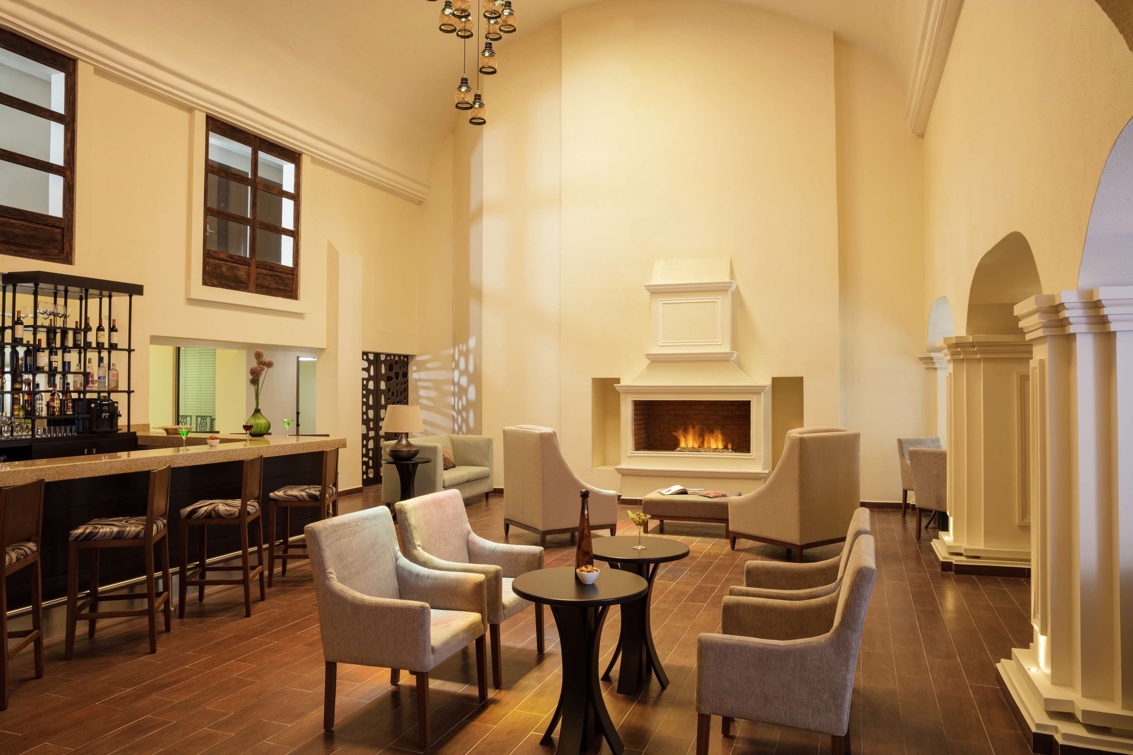 A spacious lounge area with a fireplace, comfortable seating, and a bar with a wine display.