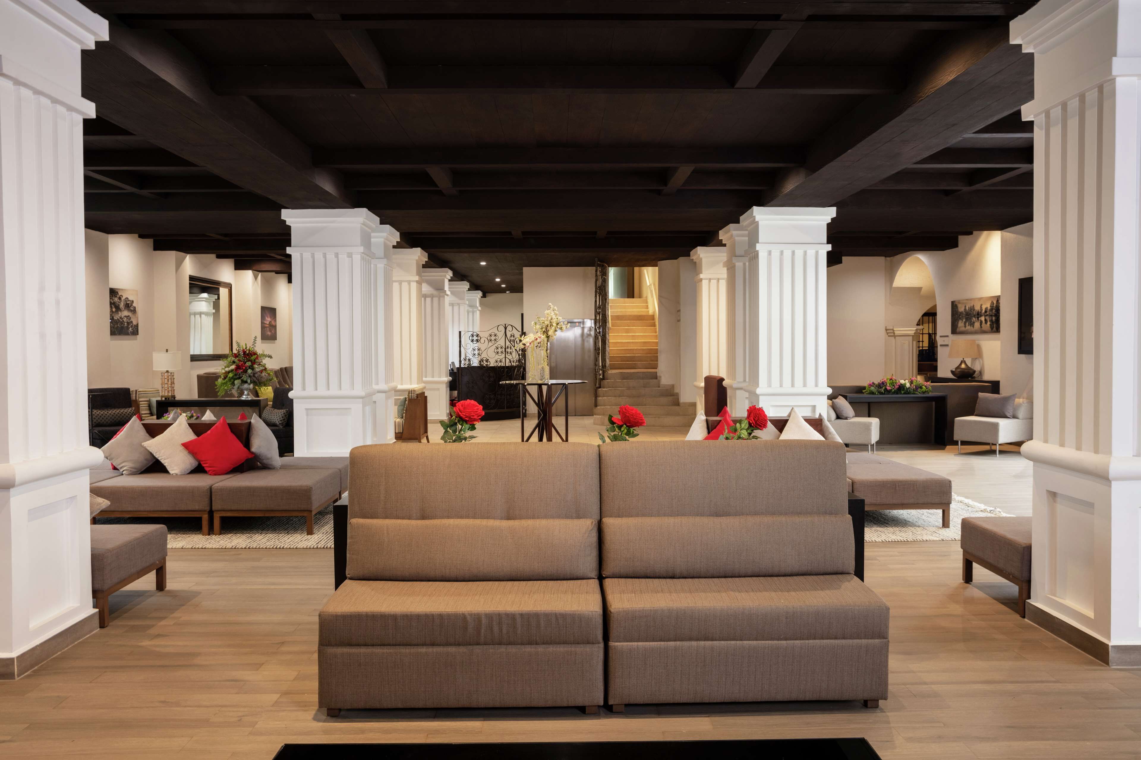 A spacious living area with a large sectional sofa, a coffee table, and a staircase leading to an upper floor.