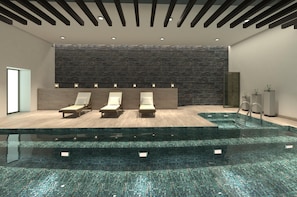 A modern indoor pool area with three lounge chairs, a stone wall, and a clear pool. - DoubleTree by Hilton Toluca (Toluca)