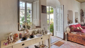 A room with a large window, a wooden dresser, and a red sofa. - La Casa de Bovedas (Arcos de la Frontera)