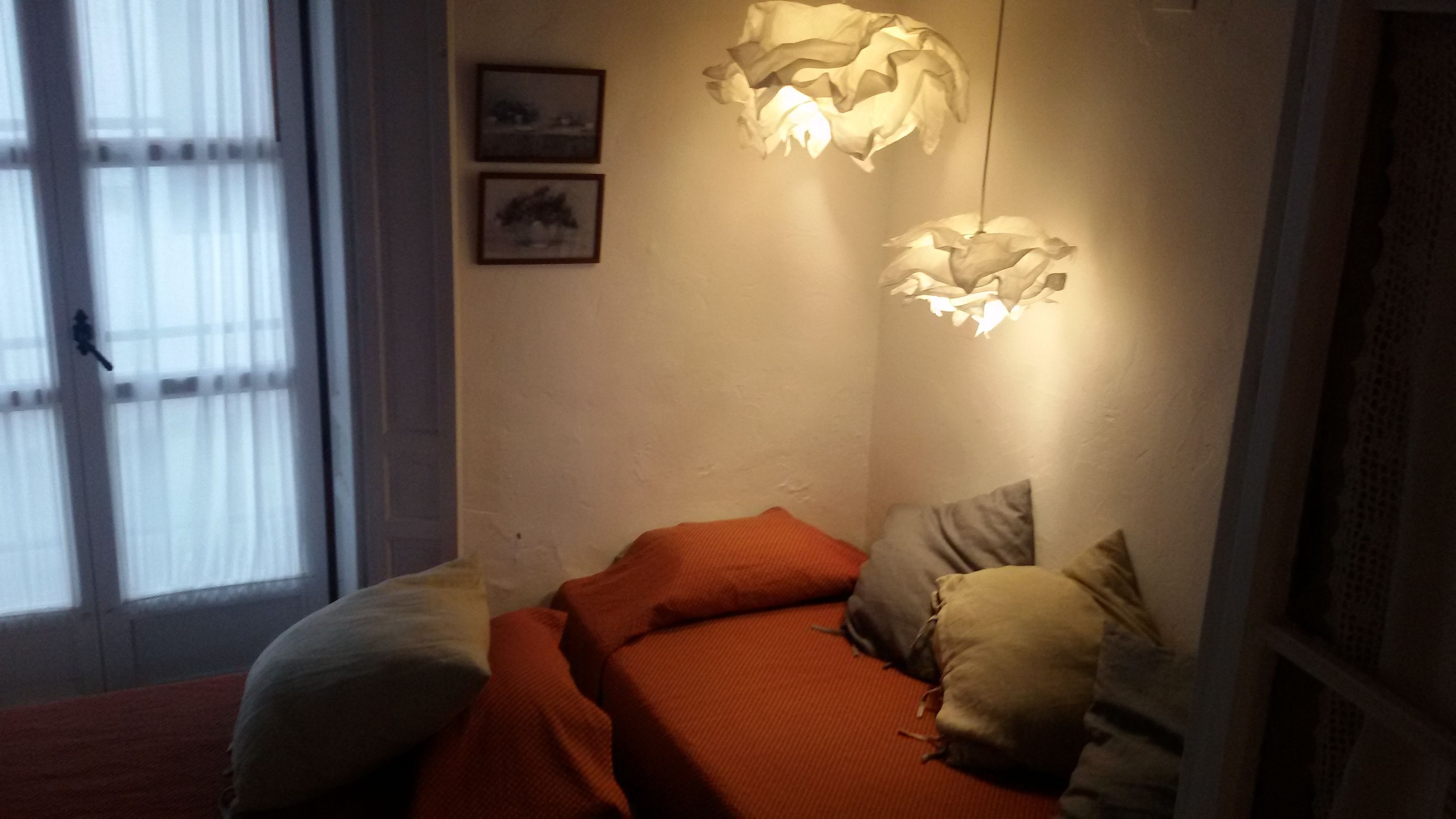 A bedroom with a bed, pillows, and a hanging light fixture.