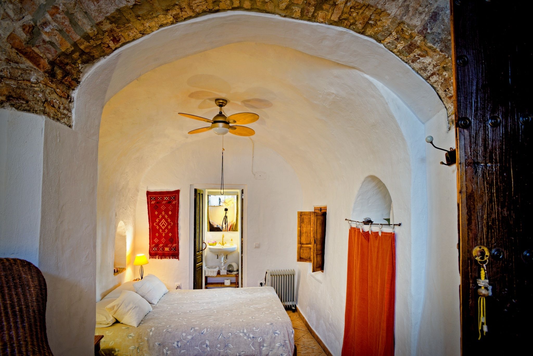 Un dormitorio con cama, ventilador de techo, ventana y puerta.
