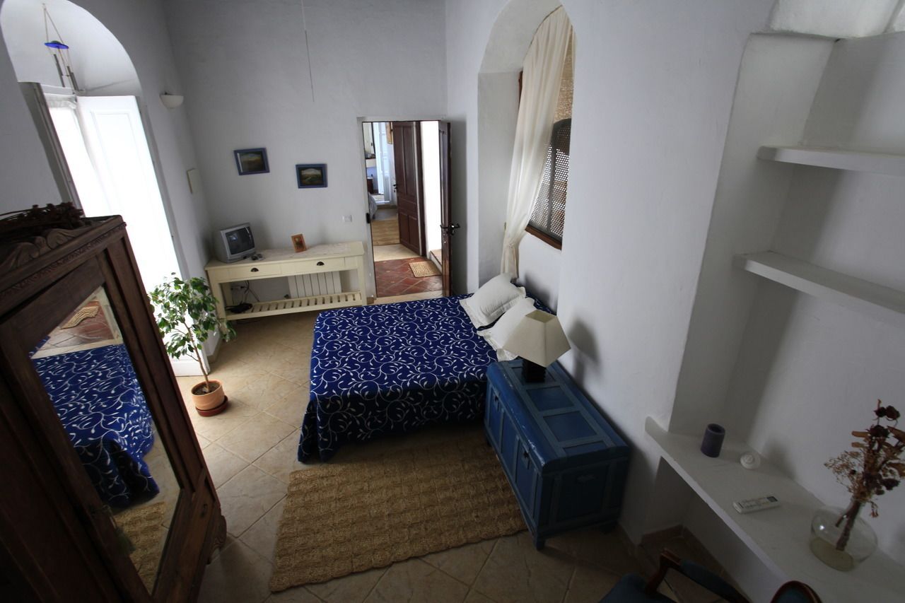 A bedroom with a bed, bedside table, dresser, and a potted plant.