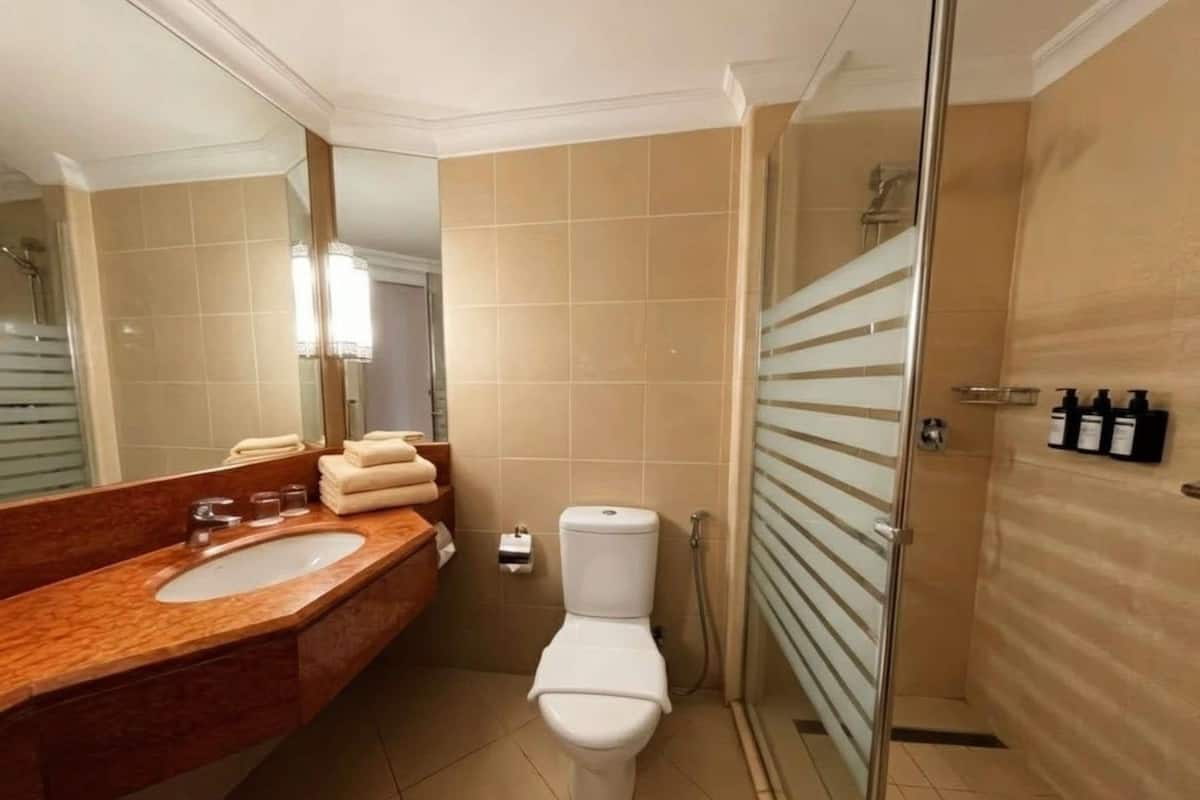 Un baño con tocador doble, inodoro y ducha con mampara de vidrio.