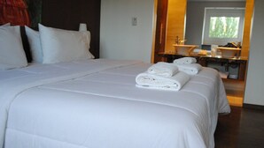 Habitación de hotel con una cama grande, baño con lavamanos y espejo, y vistas al exterior.