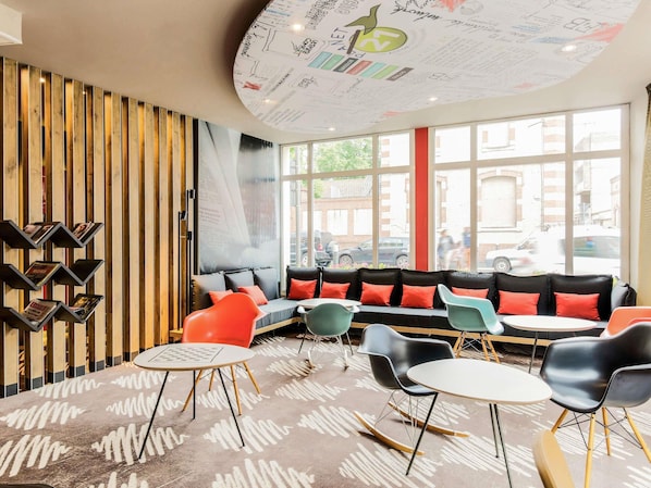 Un intérieur moderne avec un mur composé de lambris en bois, un plafond incurvé orné de croquis, un coin salon avec des coussins colorés et une vue dégagée grâce à de grandes fenêtres.