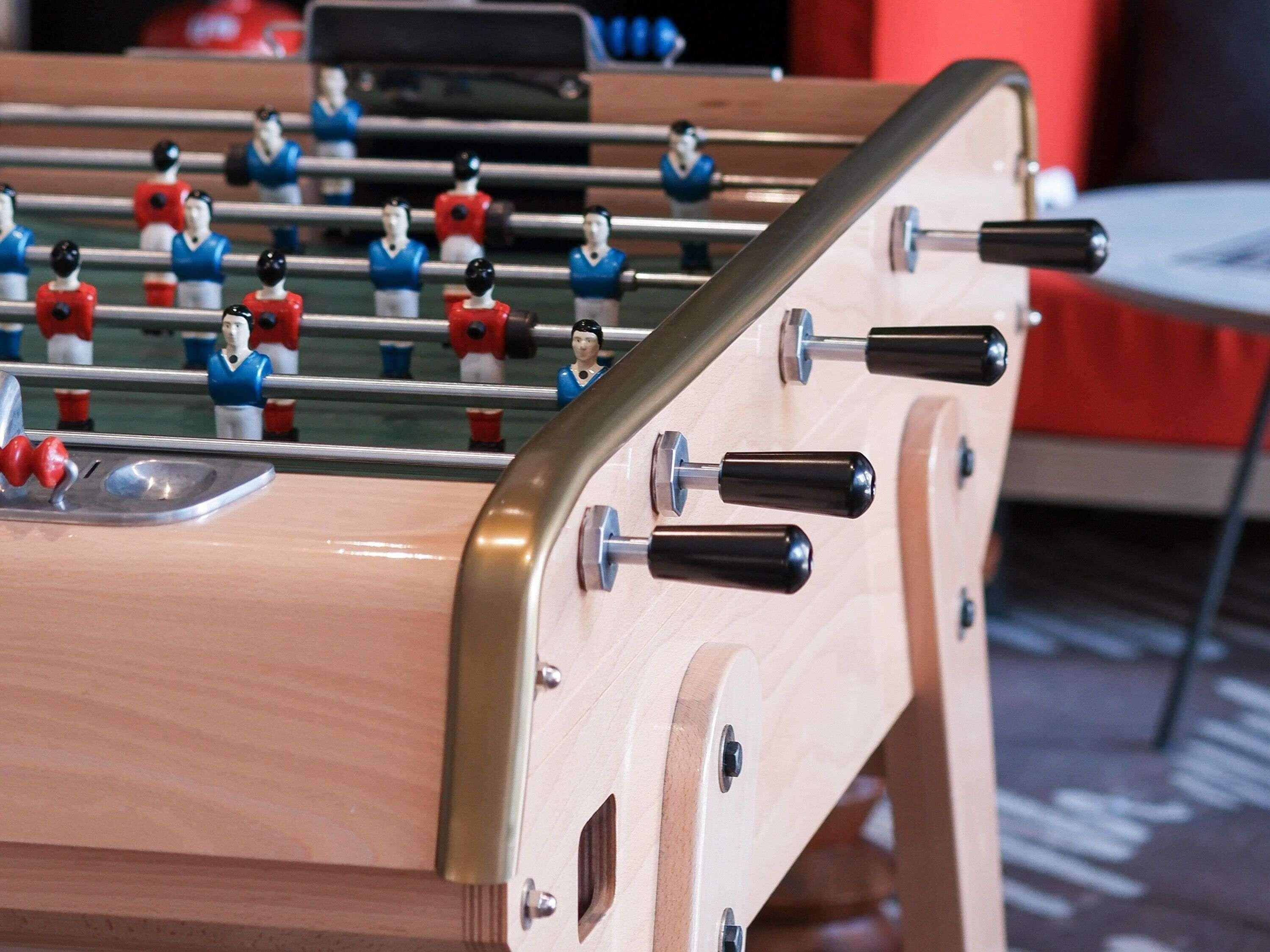 A wooden foosball table with metal rods and black handles.
