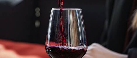 A wine glass being filled with red wine.