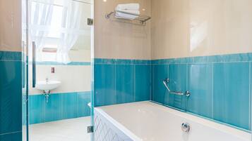 A modern bathroom with a bathtub, a glass shower enclosure, and a sink.
