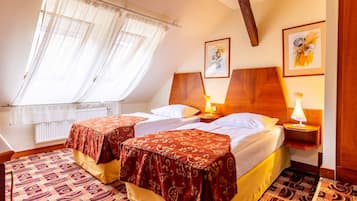 A hotel room with two beds, a window with sheer curtains, a wooden headboard, and a patterned carpet.