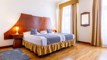 Una cama doble con cabecera de madera, dos lámparas de noche y una colcha de color azul y blanco con estampado.