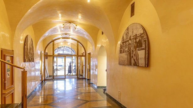 Un pasillo de hotel con suelo de mármol, techos abovedados y un cuadro grande en la pared.
