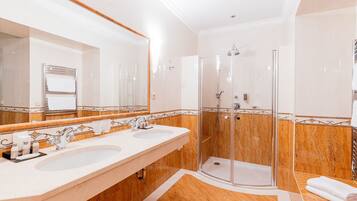 A modern bathroom with two sinks, a large mirror, and a glass-enclosed shower.