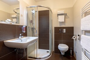 Ein modernes Badezimmer mit einer gläsernen Duschkabine, einem Waschbecken und einer Toilette.
