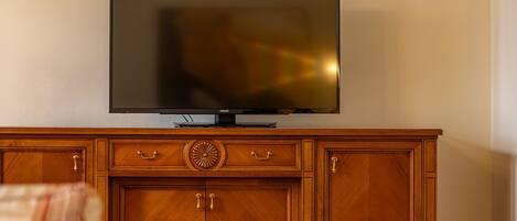 Una sala de estar con un mueble de madera, un televisor de pantalla plana y alfombras estampadas.