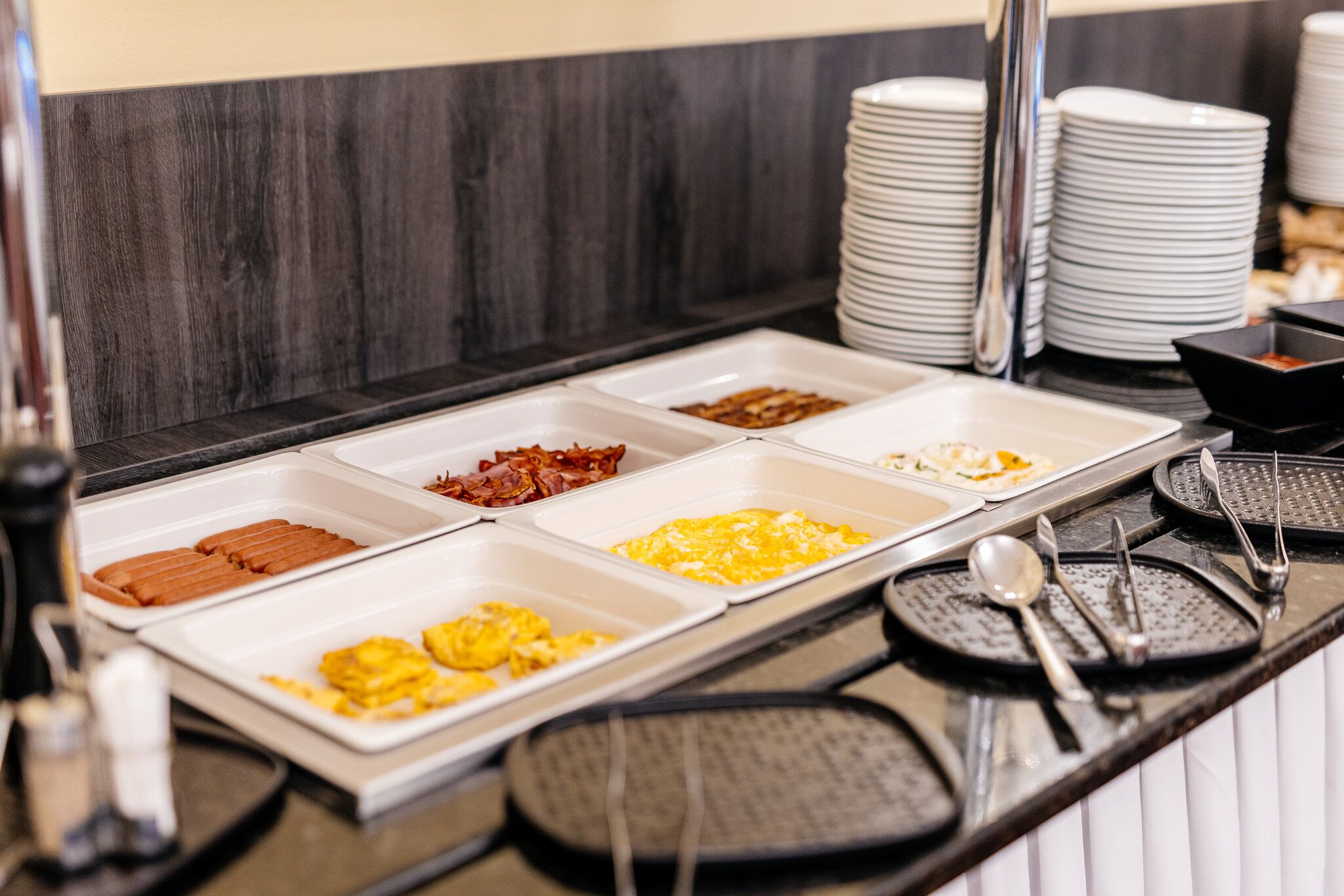 A buffet with various food options including bacon, eggs, and other breakfast items.