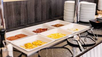 A buffet with various food options including bacon, eggs, and other breakfast items.