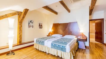 Quarto com teto de madeira, cama com colcha estampada, duas luminárias de cabeceira e mesa de cabeceira de madeira.