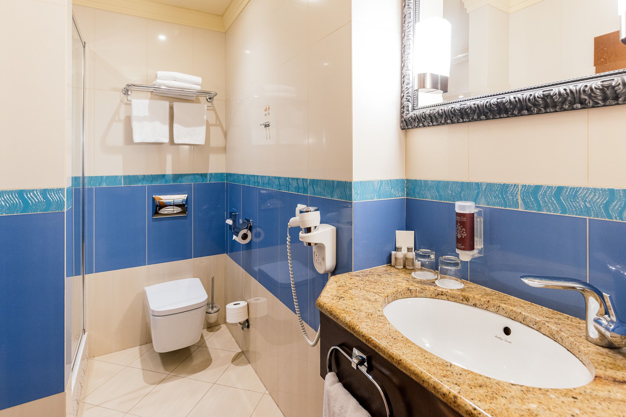 Ein Badezimmer mit Waschbecken, Spiegel, Handtuchhalter, Toilette und Dusche.