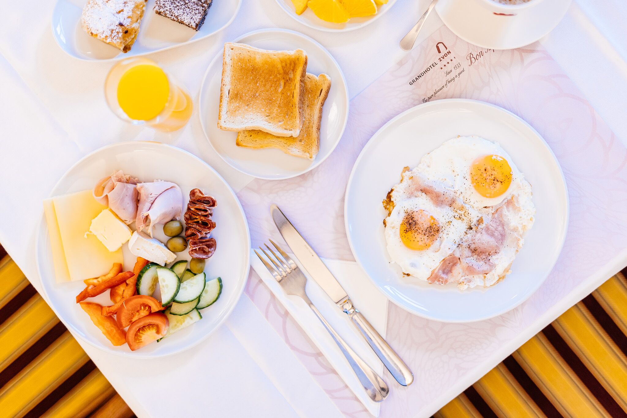 A breakfast tray with toast, eggs, cheese, ham, and vegetables.