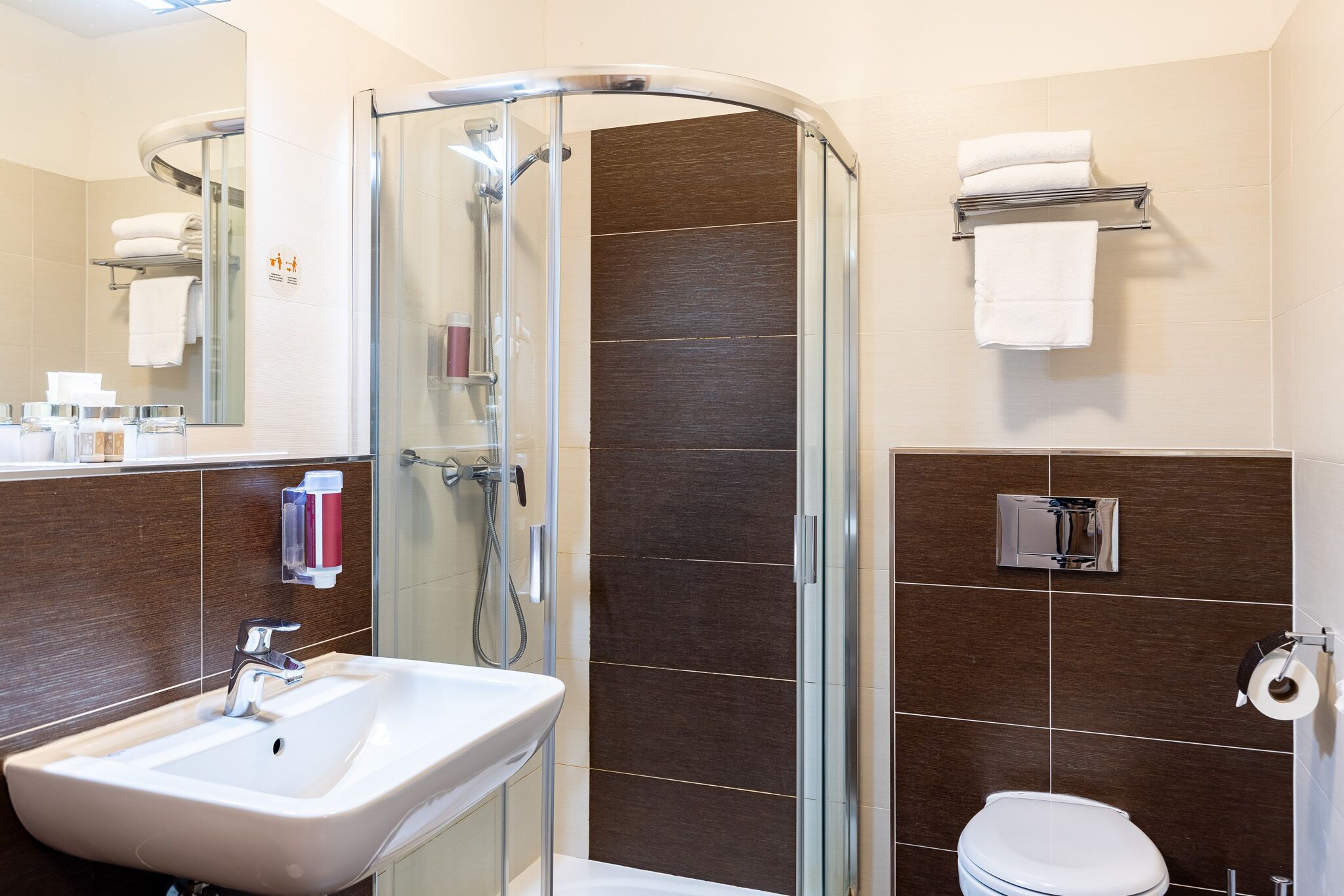 A modern bathroom with a glass-enclosed shower, a sink, a toilet, and a towel rack.