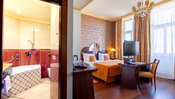 A hotel room with a shower, toilet, bed, desk, and TV.