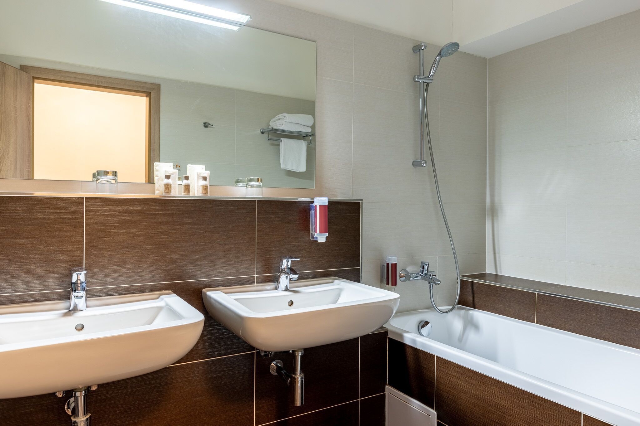 Un baño moderno con dos lavamanos, un espejo grande y una ducha.