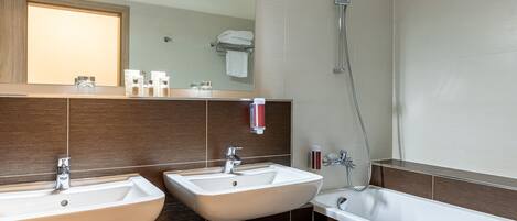 Un baño moderno con dos lavamanos, un espejo grande y una ducha.