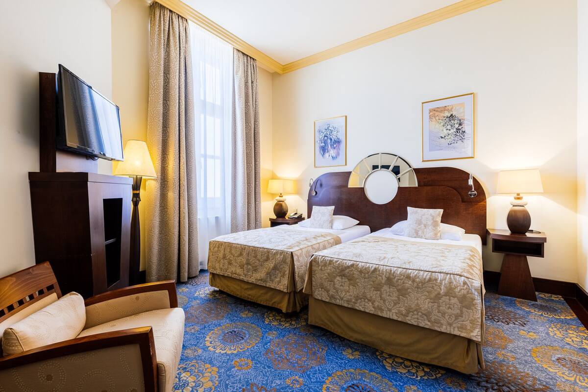 Habitación de hotel con dos camas, televisión, escritorio y una silla.