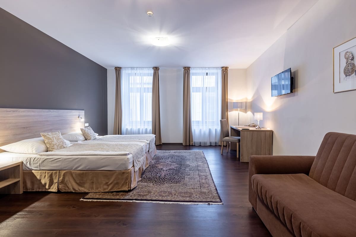 Una habitación de hotel con dos camas, un escritorio, una silla, un televisor y un sofá.