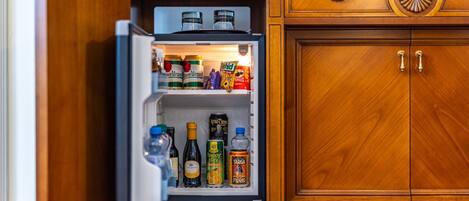 Una cocina con un armario de madera y un refrigerador lleno de diversos alimentos y bebidas.