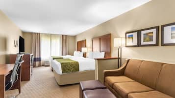 Una habitación de hotel con cama, sofá, escritorio y televisión.