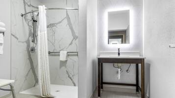 A modern bathroom with a marble shower, a vanity with a mirror, and a light fixture above the mirror.