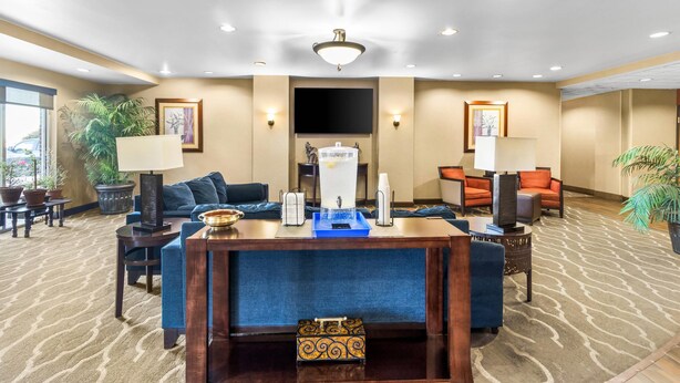 A hotel lobby with a reception desk, seating area, and a large screen TV. - Comfort Suites Mount Vernon (Mount Vernon)