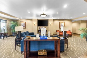 A hotel lobby with a reception desk, seating area, and a large screen TV. - Comfort Suites Mount Vernon (Mount Vernon)