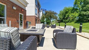 A brick building with a patio area featuring wicker furniture and a table. - Comfort Suites Mount Vernon (Mount Vernon)