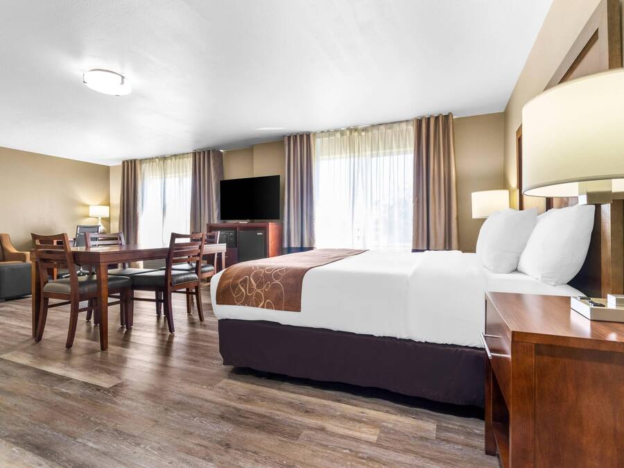 A hotel room with a bed, a desk with a chair, a sofa, and a TV.