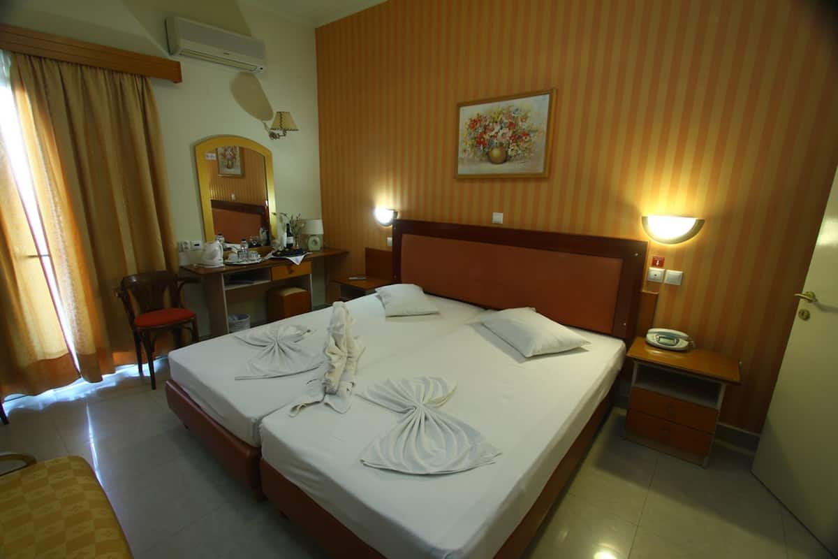 Une chambre d’hôtel avec un grand lit, un bureau avec une chaise, un miroir et un tableau au mur.