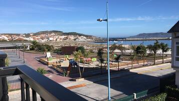 A coastal view with a playground, a street lamp, and a clear sky.