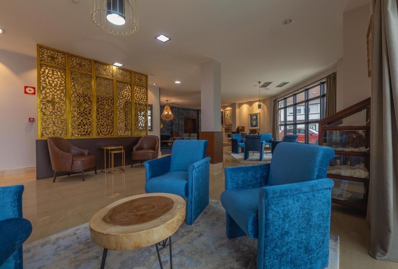 A spacious lobby with blue armchairs, a wooden coffee table, and a decorative partition.