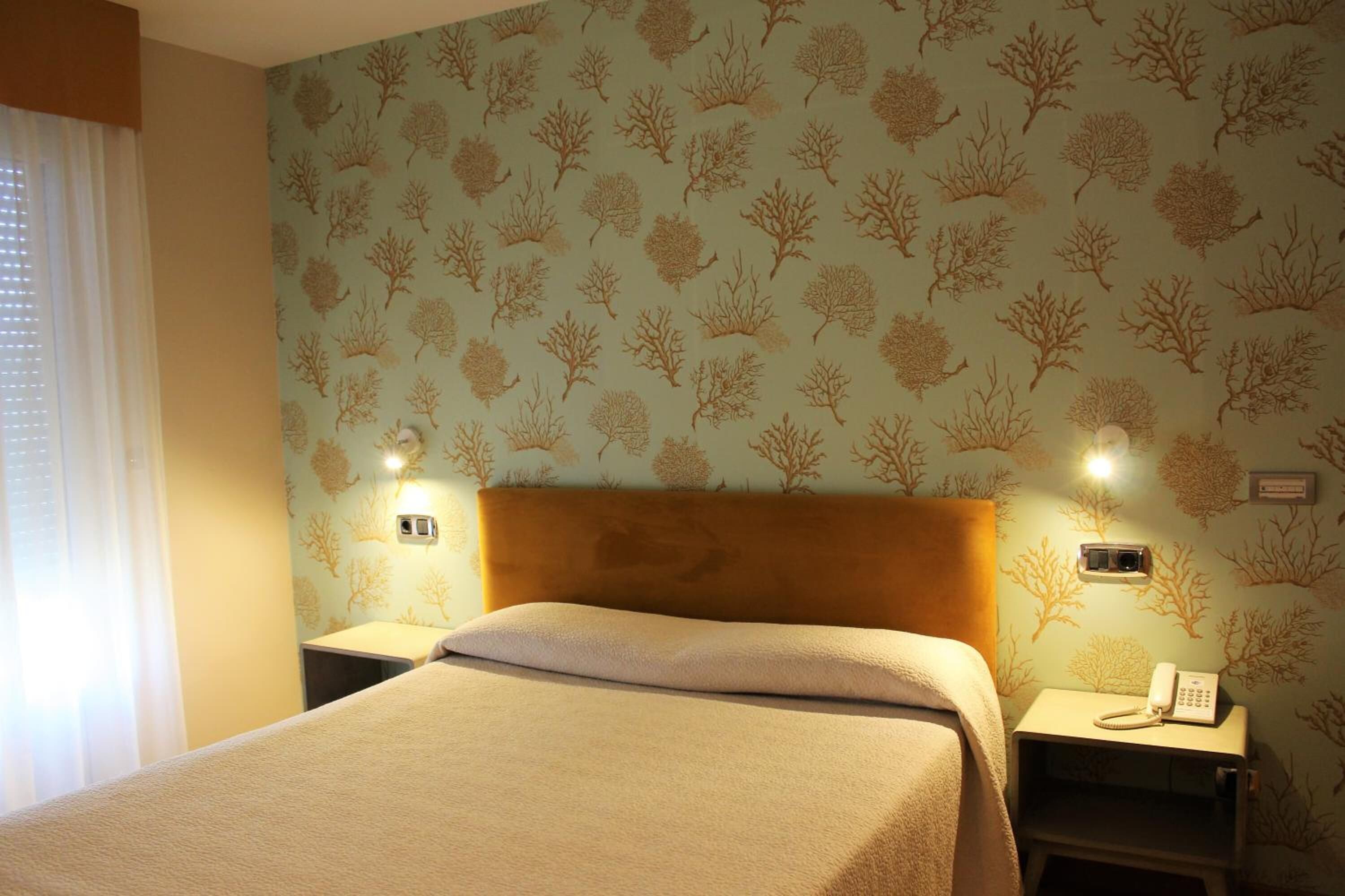 A hotel room with a bed, nightstands, and a telephone.