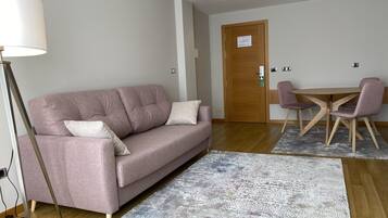 Una sala de estar moderna con un sofá rosa, una mesa de comedor de madera con sillas y una alfombra estampada.