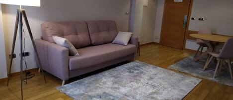 A modern living room with a sofa, a standing lamp, a rug, a small table, and chairs.