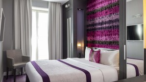 Una habitación de hotel con cama, una silla, un televisor y una pared con textura.