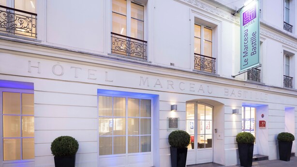 Fachada del Hotel Le Marceau Bastille, con un estilo arquitectónico clásico, grandes ventanales y elaboradas barandillas de hierro.