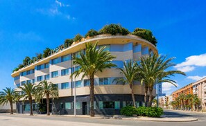 A hotel with a curved facade, multiple floors, and palm trees in front.
